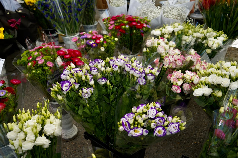 A variety of fresh flower bouquets arranged on a dark countertop, showcasing vibrant colors and different floral types. Prominent in the foreground are purple and white lisianthus flowers with delicat