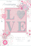 This anniversary card presents a tender, romantic design that feels as intimate as a quiet stroll through the side streets of Lisson Grove on a soft spring evening. At the centre, the word LOVE is spelled out in elevated, velvety glitter, each letter pale pink with a gentle shimmer. The letter O is replaced by a gleaming silver heart, slightly textured so it would catch under the fingertips, symbolising the shared centre of a lasting relationship. This central motif rests on a blush-pink panel, bordered by soft tones of pastel pink and silvery grey that create a calm, nurturing backdrop. Around it, delicate blossoms in blush, mauve, and ivory unfurl with a watercolour softness, their edges lightly defined with silver accents that sparkle like streetlights reflected on evening pavements near Marylebone and Regent's Park. Swirls of fine vines, drifting petals, and tiny butterflies weave through the design, suggesting both movement and a gentle sense of celebration, much like a bouquet arriving for an anniversary delivery in one of the townhouses off Lisson Grove. The phrases On Our Anniversary and I love you today and always appear in an elegant, understated script, placed so they seem to grow naturally from the floral arrangement. There is a softness to the entire composition, from the muted pastel palette to the flowing lines, creating the feeling of an English spring garden translated into paper. The card balances intimacy and occasion, ideal for marking years of shared stories and quiet companionship, its tactile glitter and intricate floral details turning a simple message into a keepsake of enduring romance.